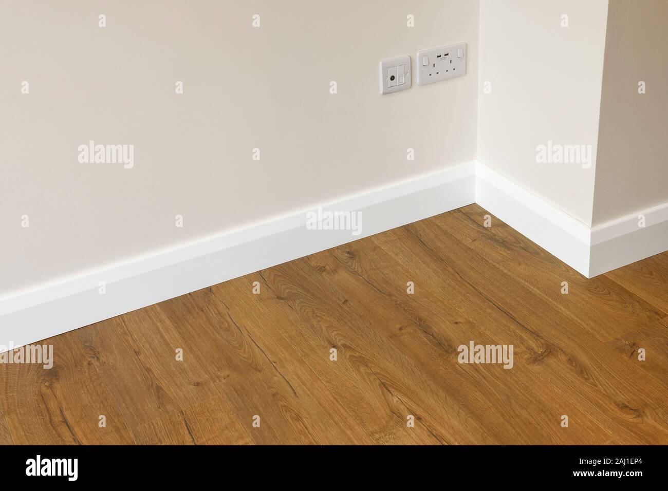 Close up detail of oak effect laminate flooring adjacent to a wall and skirting board Stock Photo