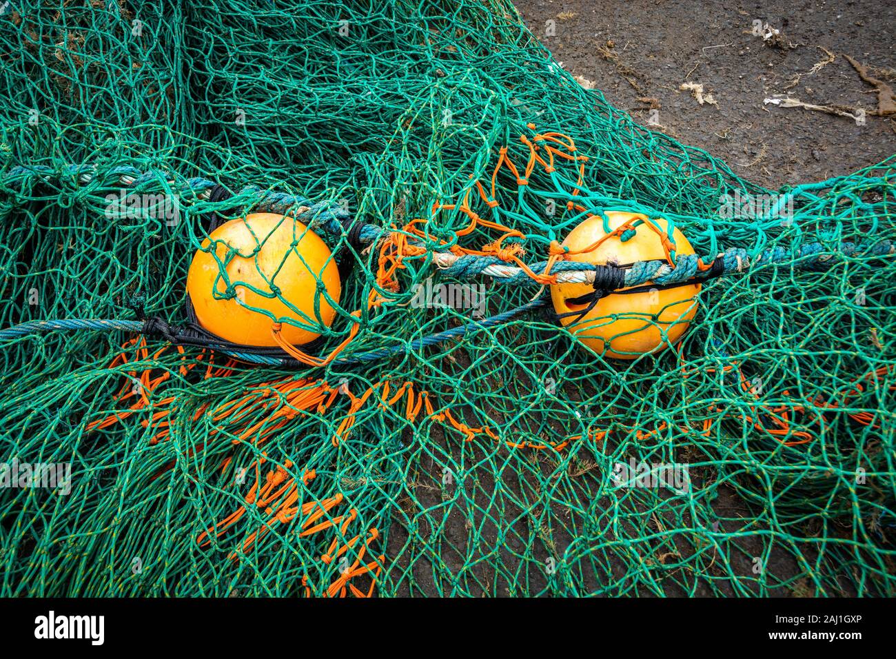 Fishing net on the ground with two yellow buoys Stock Photo