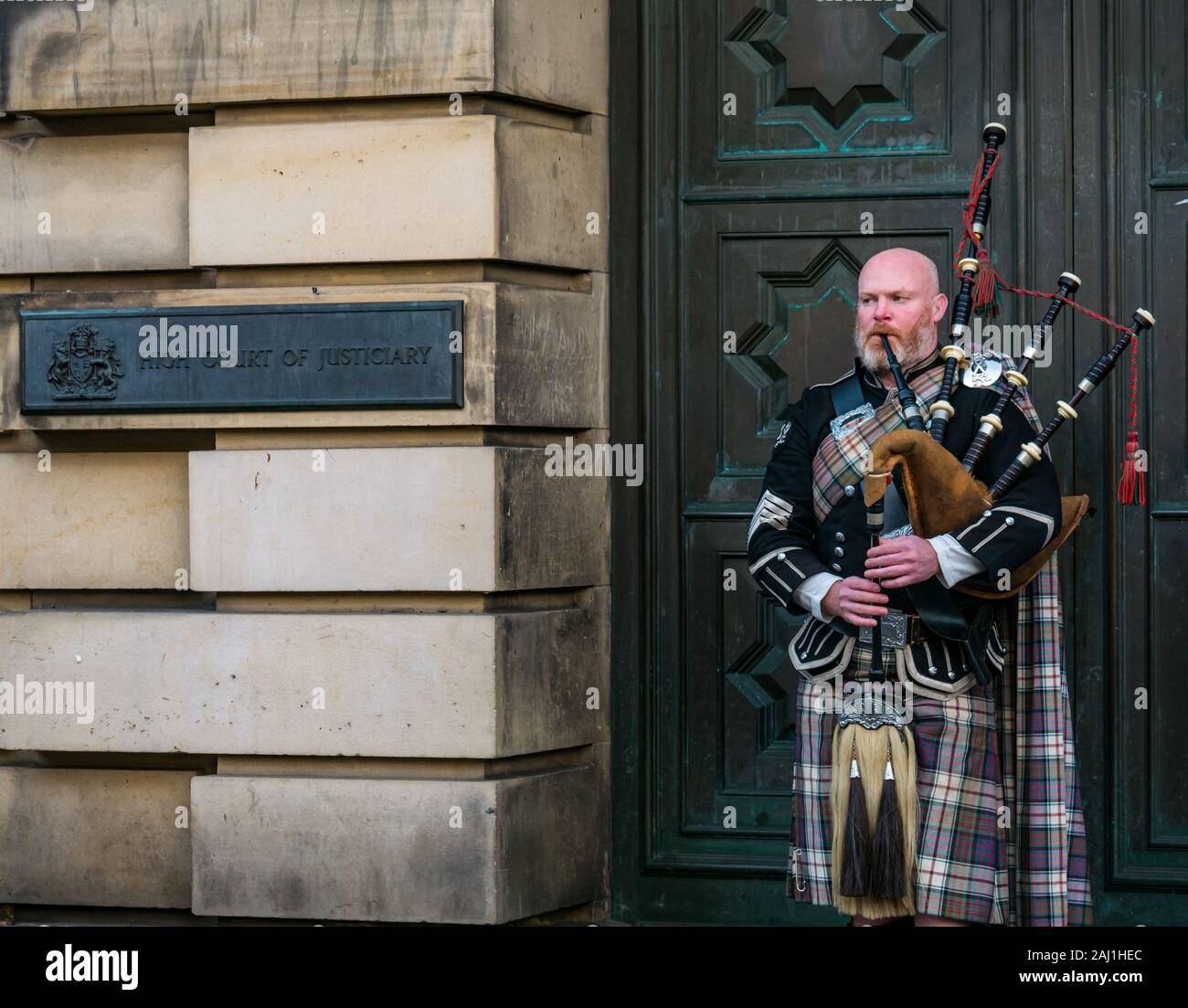 Bagpipe player busker outside High Court of Justiciary, Royal Mile, Edinburgh, Scotland, UK Stock Photo