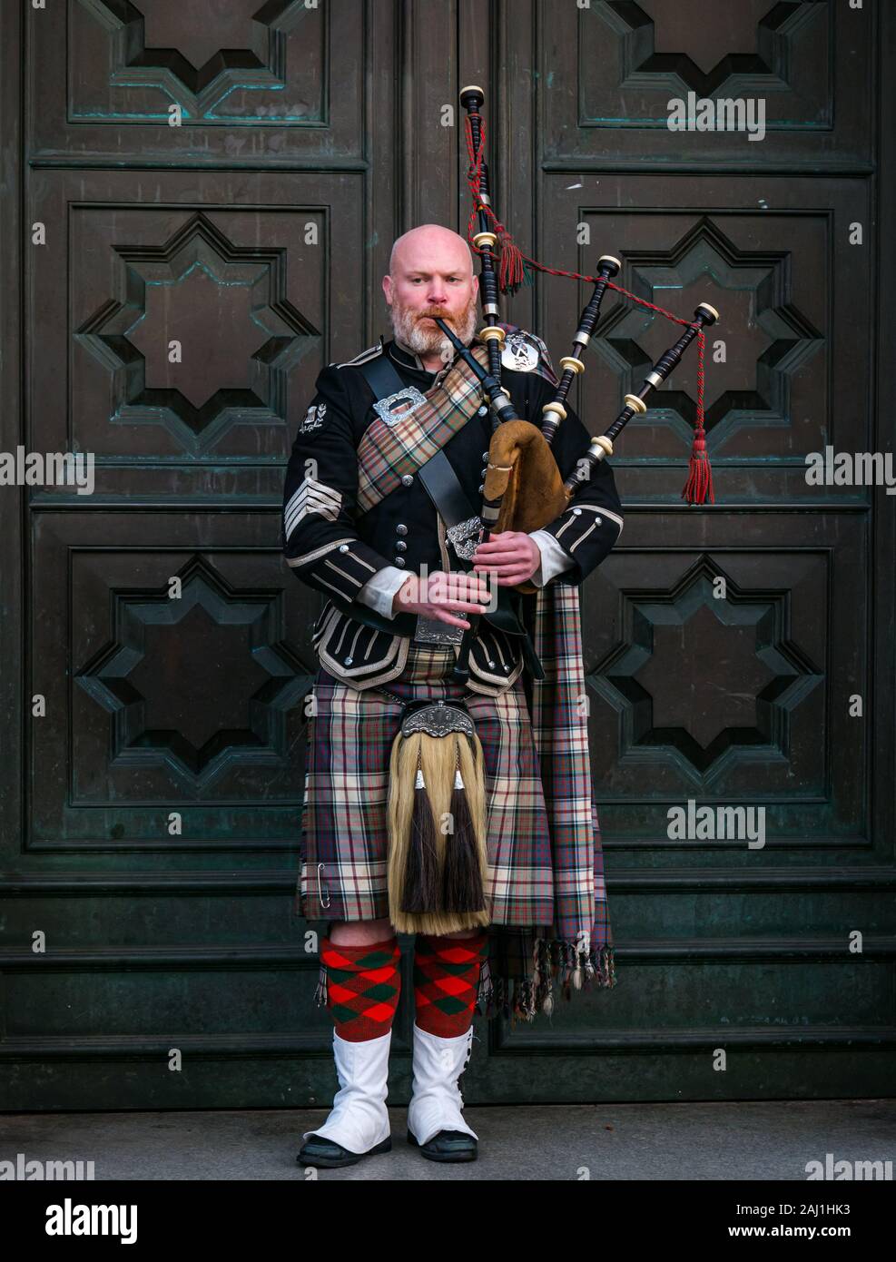 Bagpipe player busker outside High Court of Justiciary, Royal Mile, Edinburgh, Scotland, UK Stock Photo