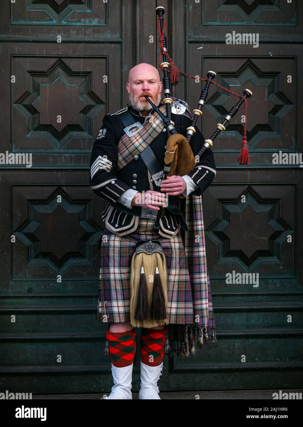 Bagpipe player busker outside High Court of Justiciary, Royal Mile, Edinburgh, Scotland, UK Stock Photo