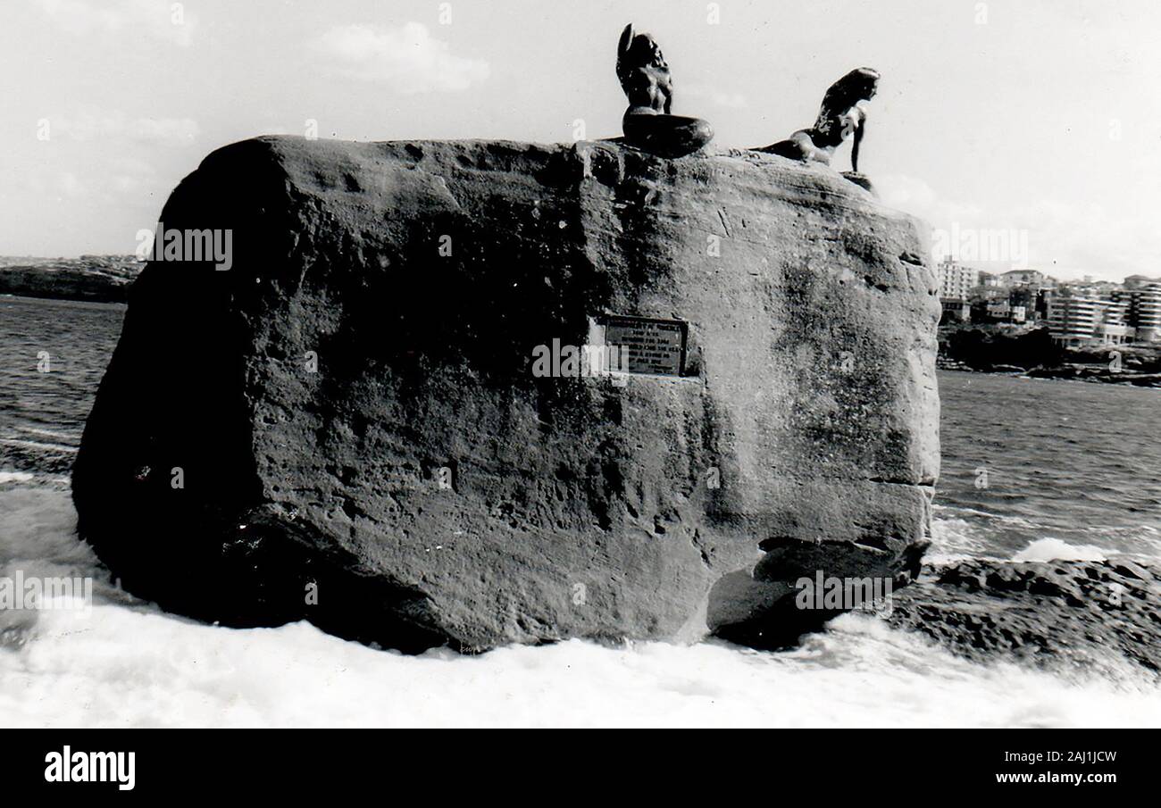 July 1971 - Mermaid rock, Bondi Beach, Australia,(when the mermaids were still intact). The rock (235 tons) itself was allegedly washed ashore during a storm on 15th July 1912. The mermaids were created by sculptor Lyall Randolph (installed 3 April 1960) were modelled on two local women  Jan Carmody, (Miss Australia Surf 1959) and Lynette Whillier, (champion swimmer and runner-up in the same contest.). Lynette was lost to the sea in 1974, the other with one arm missing was removed in 1976 and is preserved in Waverley library. Both were made from bronze coloured fiberglass. Stock Photo