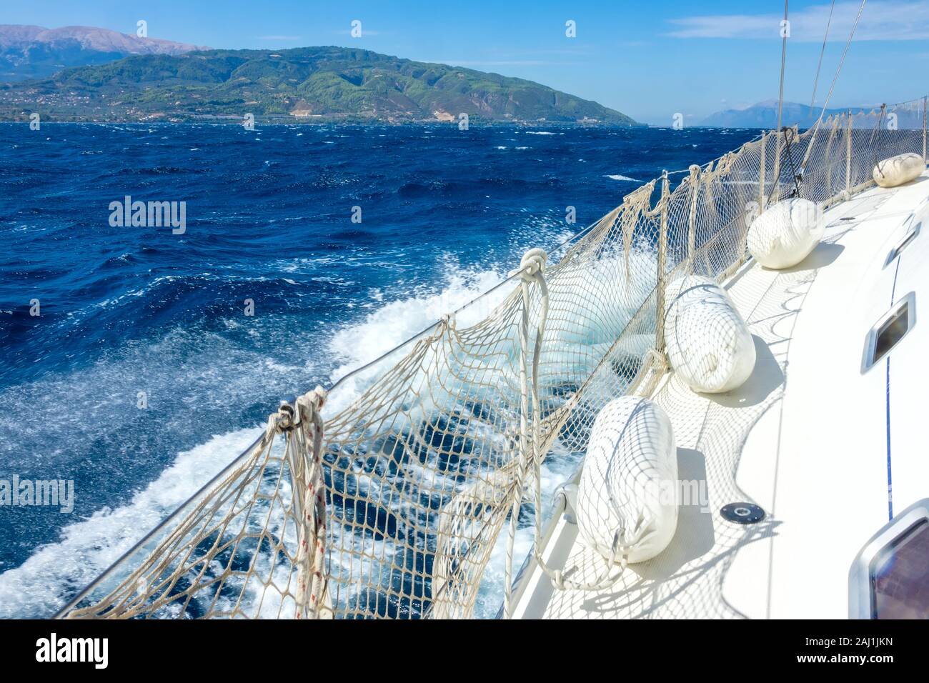 The port of a sailing yacht with a guard rail and fenders. Windy sunny day. Deep blue sea and sea foam Stock Photo