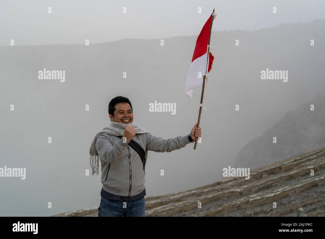 A tourist holds the Indonesian national flag and poses for a photograph