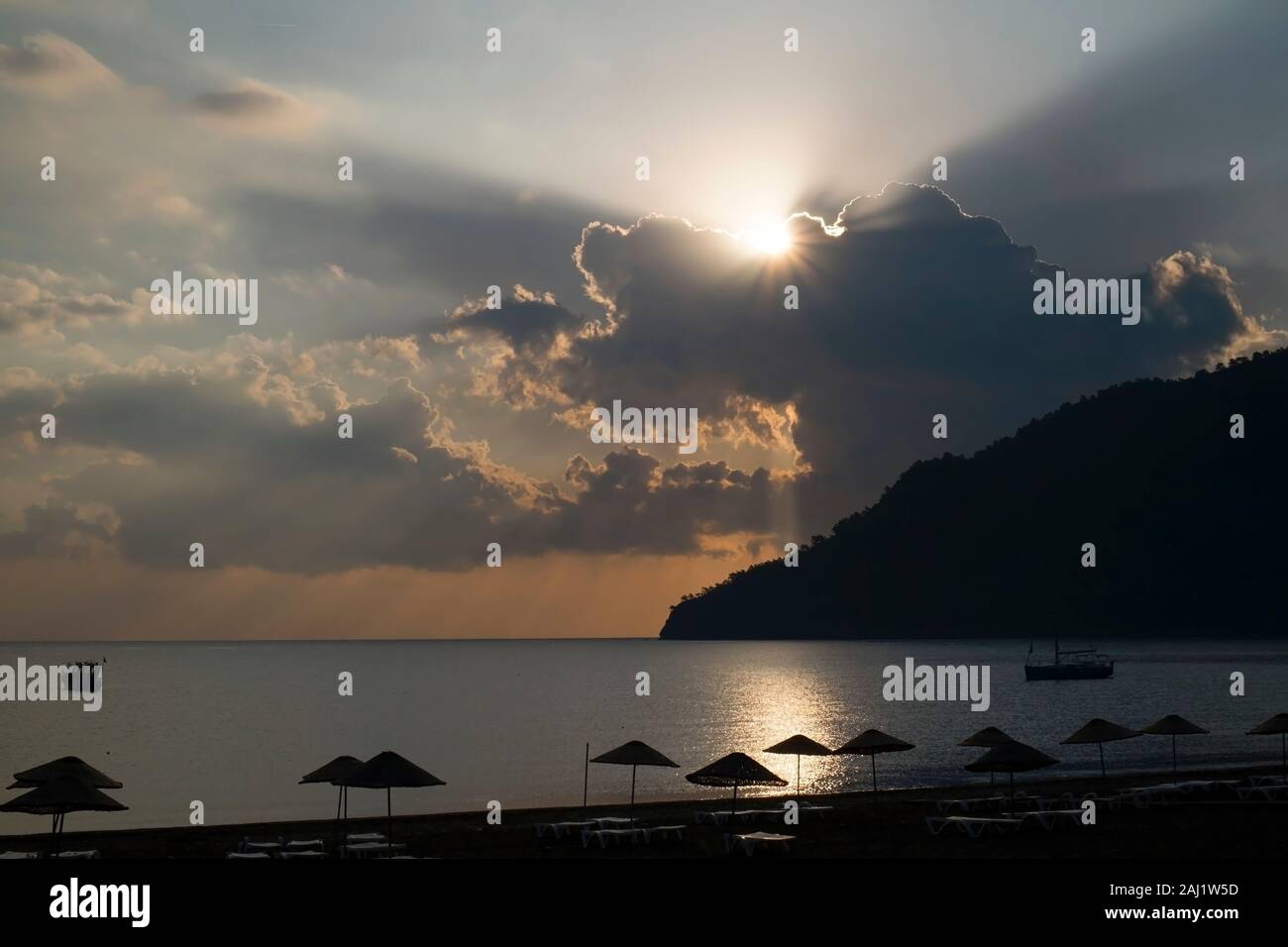 Wonderful sunset at The Beach Of Adrasan, Antalya Province at Turkey. Sunbeams were perfect when sun is hiding behind clouds. Stock Photo