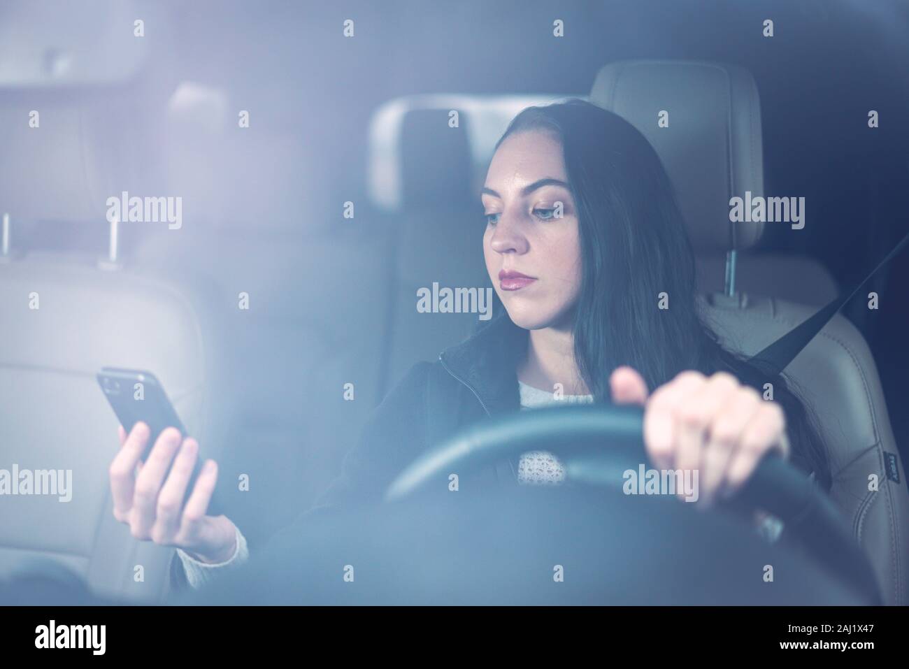 Beautiful young millennial woman texting and driving Stock Photo