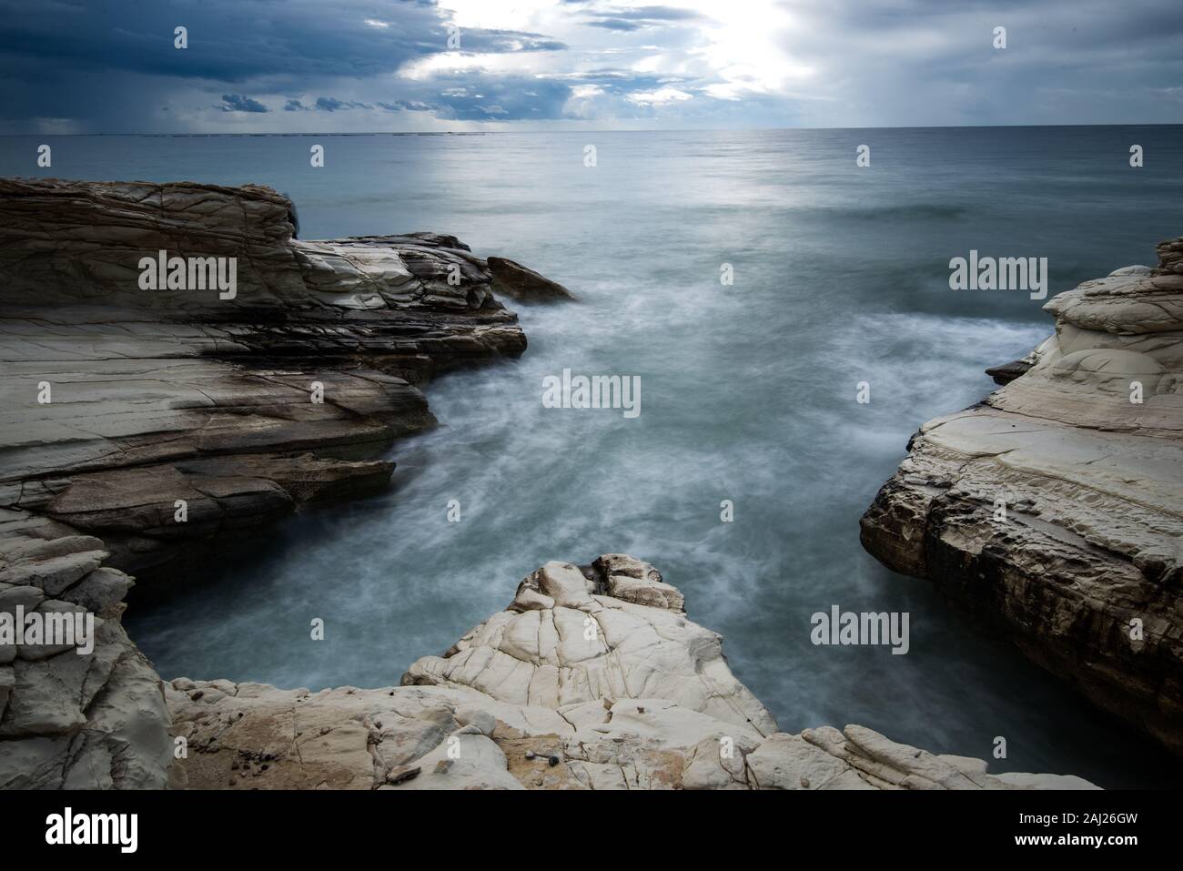 Rocky seashore seascape with wavy ocean and dramatic sky at the coastal area  in Limassol, Cyprus. Long exposure photography Stock Photo