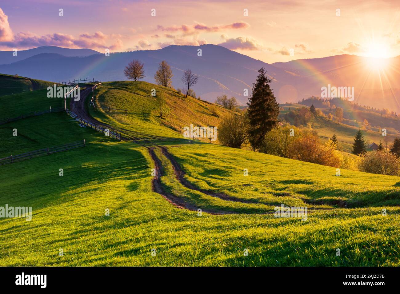 Mountainous Rural Landscape In Evening Light Wooden Fence Along The Path Through Rolling Hills In Fresh Green Grass Beautiful Scenery In Springtime Stock Photo Alamy Mountainous Rural Landscape In Evening Light Wooden Fence Along The Path Through Rolling Hills In Fresh Green Grass Beautiful Scenery In Springtime Stock Photo Alamy