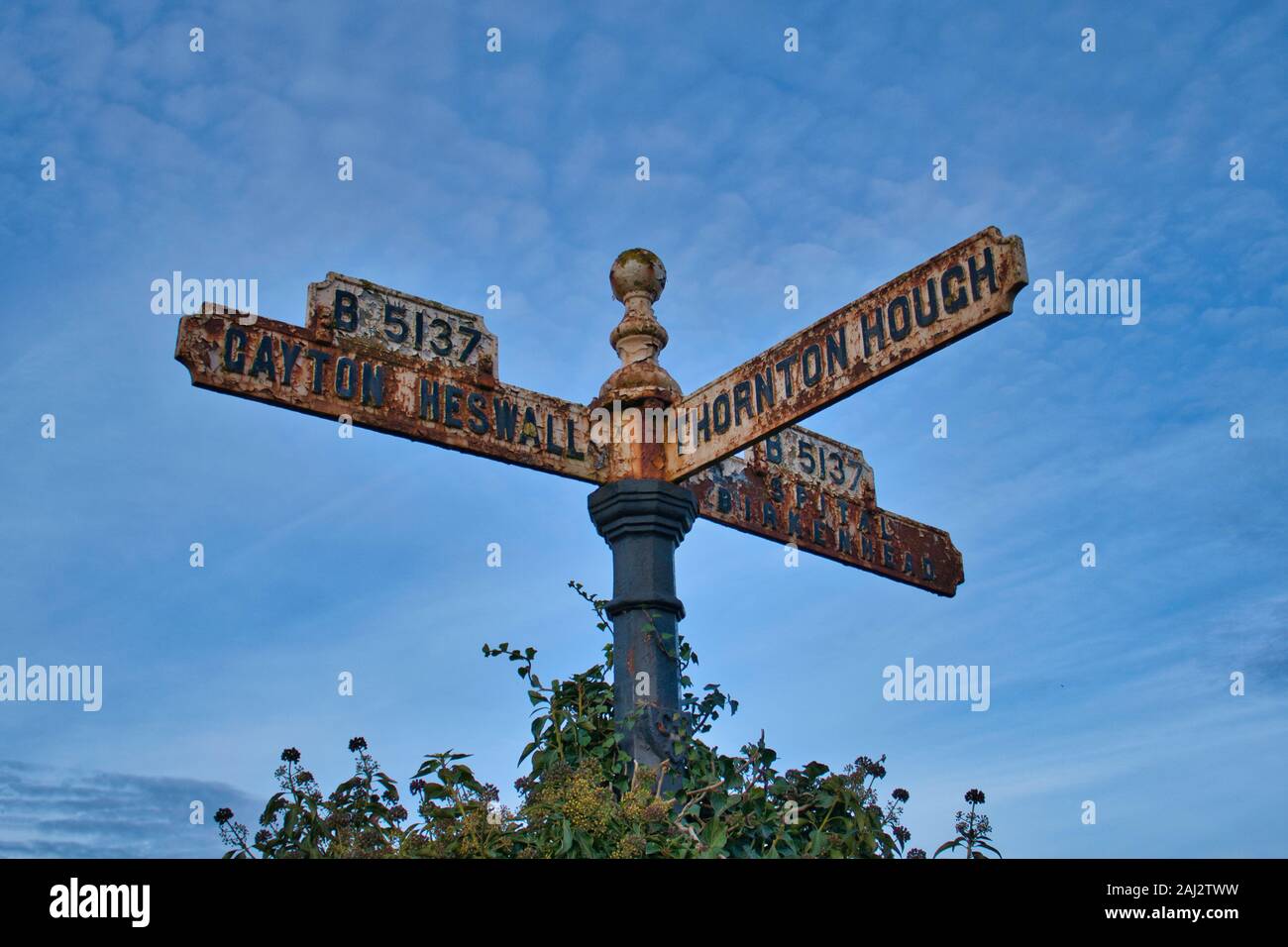 An old, rusting sign showing directions to Gayton, Heswall, Thornton Hough and Birkenhead in Wirral, UK Stock Photo