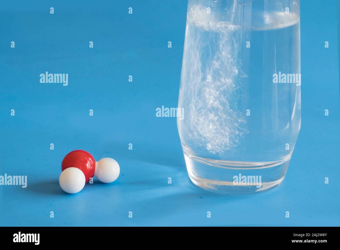Glass of liquid water and the H2O molecule with one hydrogen and two oxygen atoms . Stock Photo