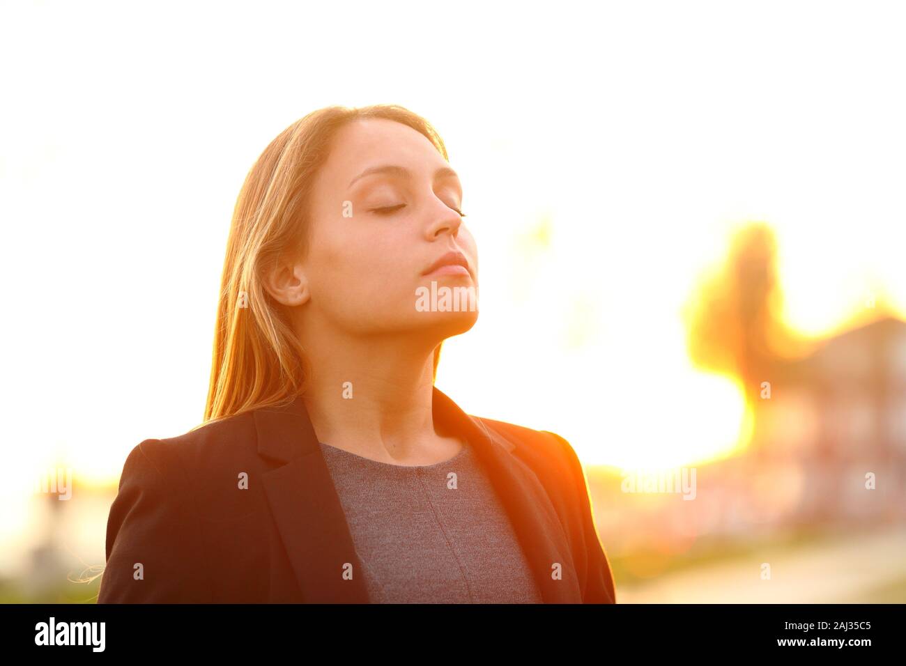 Serious businesswoman breathing fresh air at sunset standing outdoors Stock Photo