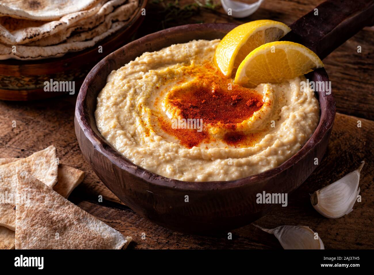A bowl of creamy delicious middle eastern style hummus with lemon garnish. Stock Photo