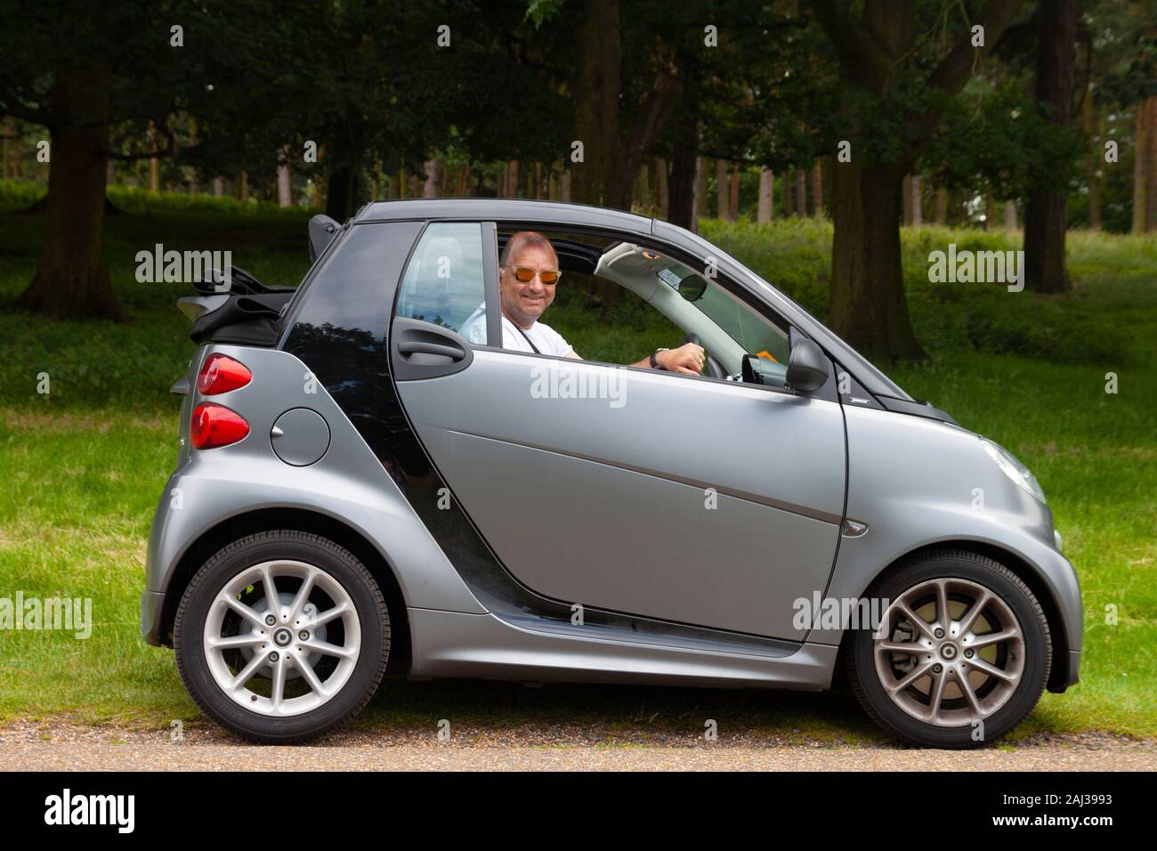 smiling middle aged cool man in Smart Car with soft top Stock Photo