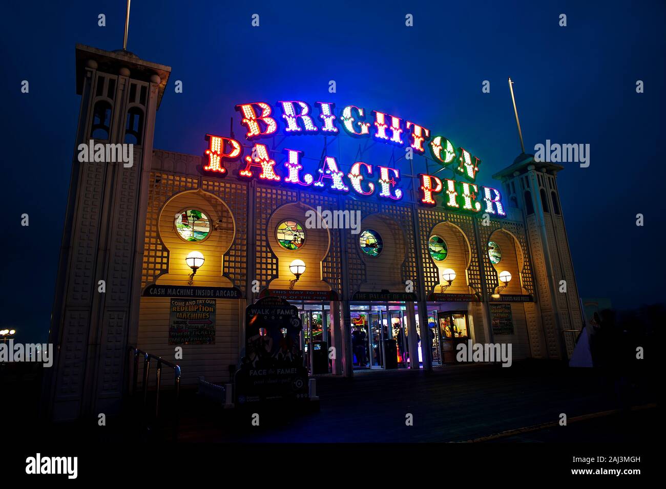 The colourful illuminated sign of Brighton Palace Pier is lit up at night. The famous pier is one of the U.K.'s most popular visitor destinations. Stock Photo