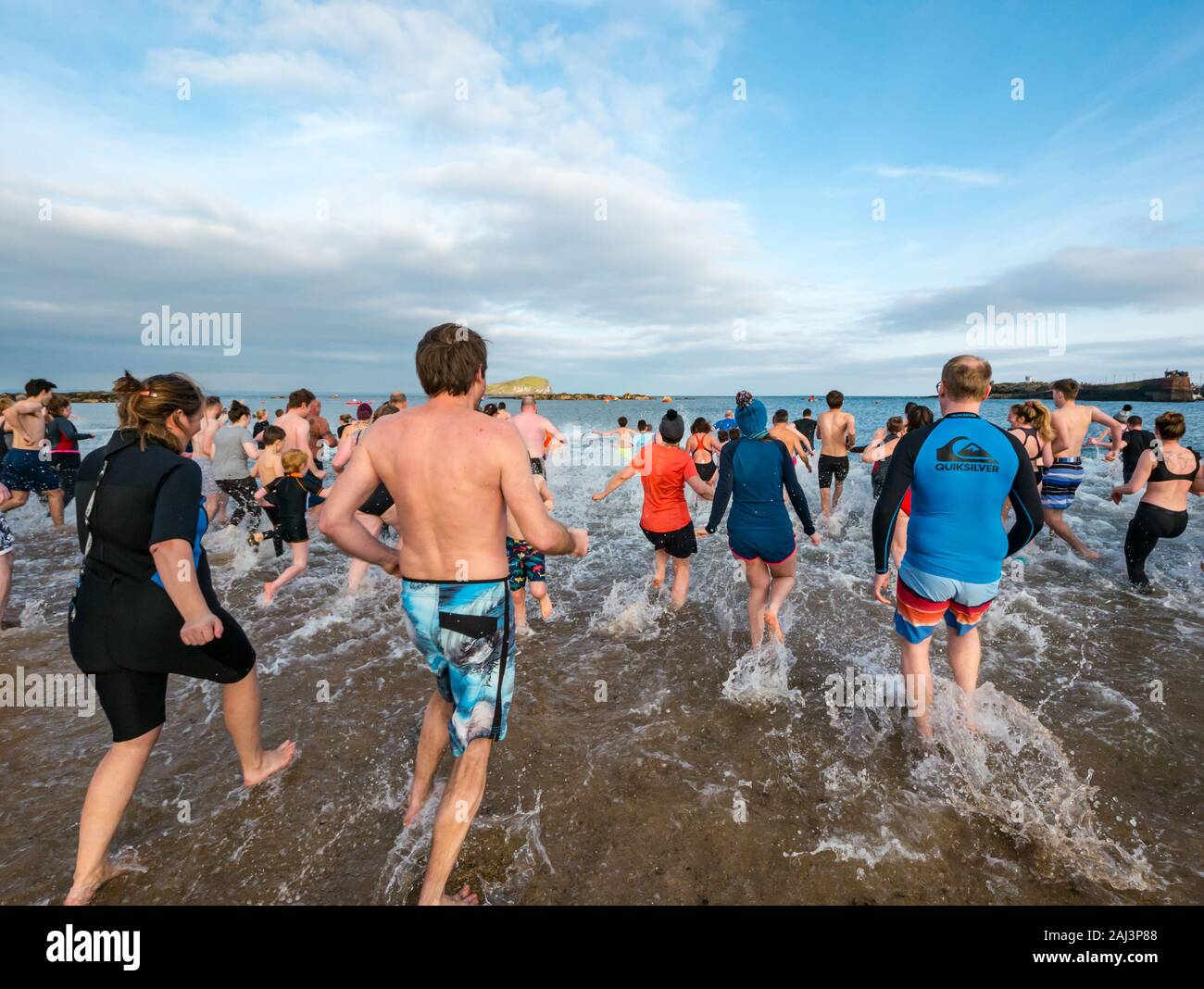 People run into the sea for 2020 New Year's Loony Dook or Dip, North Berwick, East Lothian, Scotland, UK Stock Photo