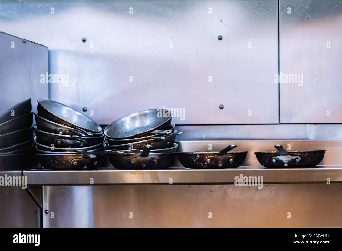 Lots of dirty pans, restaurant commercial cuisine, utensil stacked on top of each other on