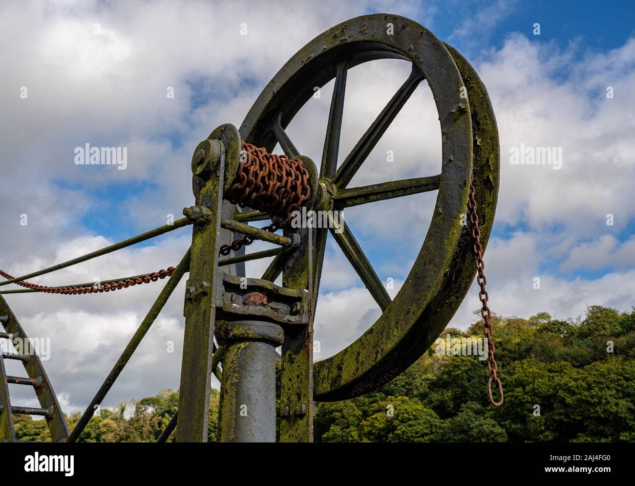 Rusty old metal winch or crane for cargo by the tidal River Tamar at Cotehele in Devon Stock Photo
