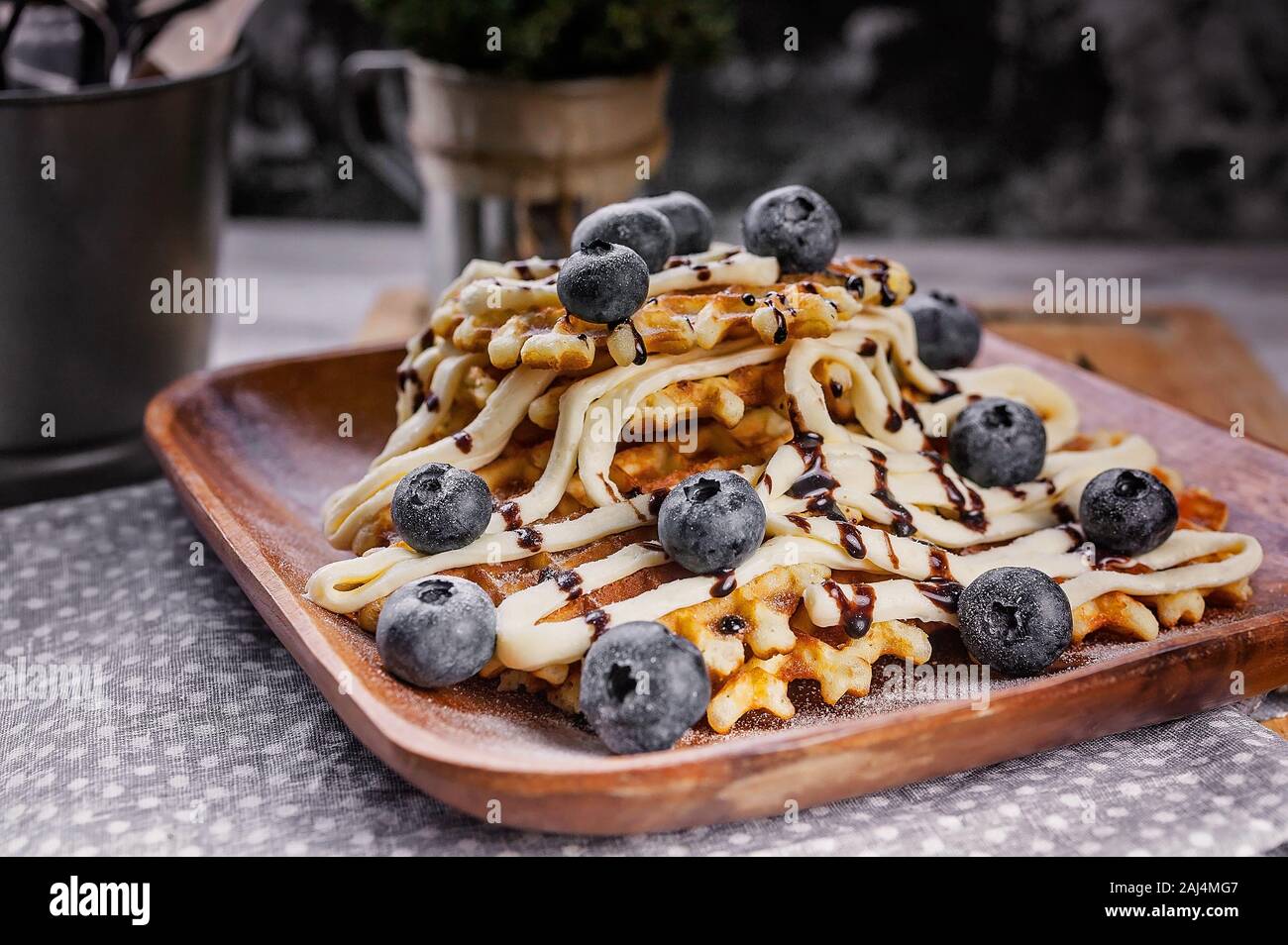 Close-up waffles with butter cream, chocolate and blueberries. Sweet dessert. Homemade baking. Stock Photo