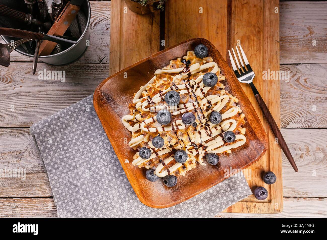 Top view homemade baking. Waffles with butter cream, chocolate and blueberries. Sweet dessert. Stock Photo