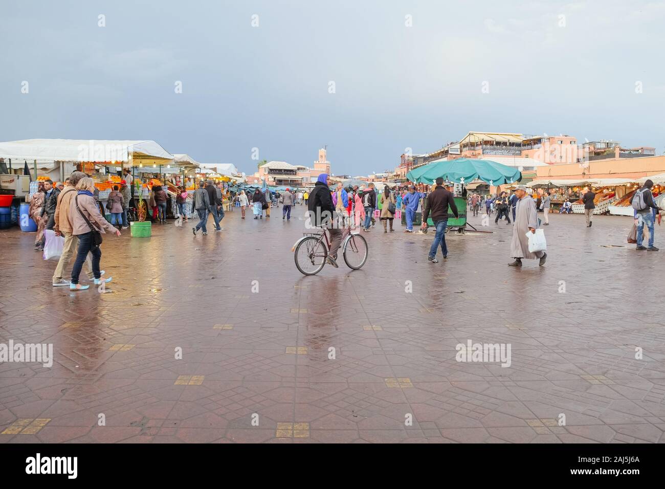 People walking and cycling around the old street market for shopping and sightseeing at Djemaa el-Fnaa square. Medina Marrakesh,Morocco. Stock Photo
