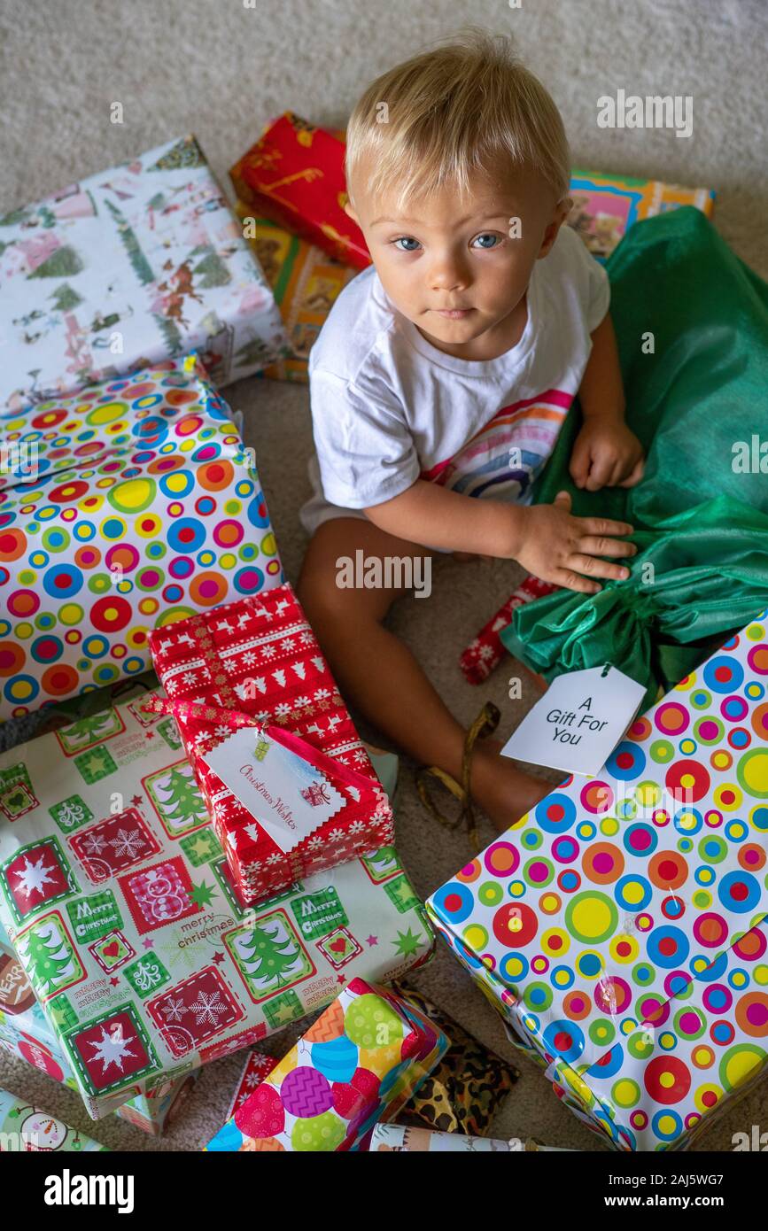 A Cute Baby Sitting With Christmas Presents Stock Photo