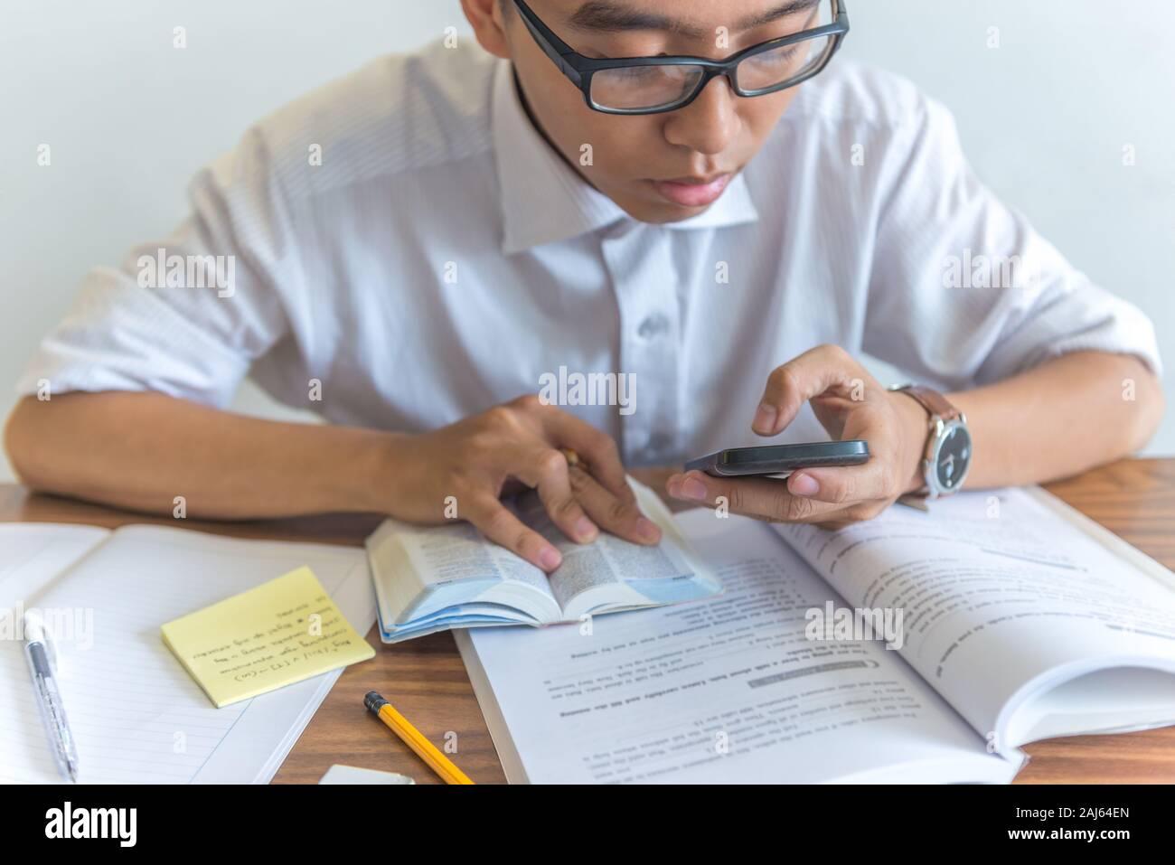Young student using smartphone and doing homework Stock Photo