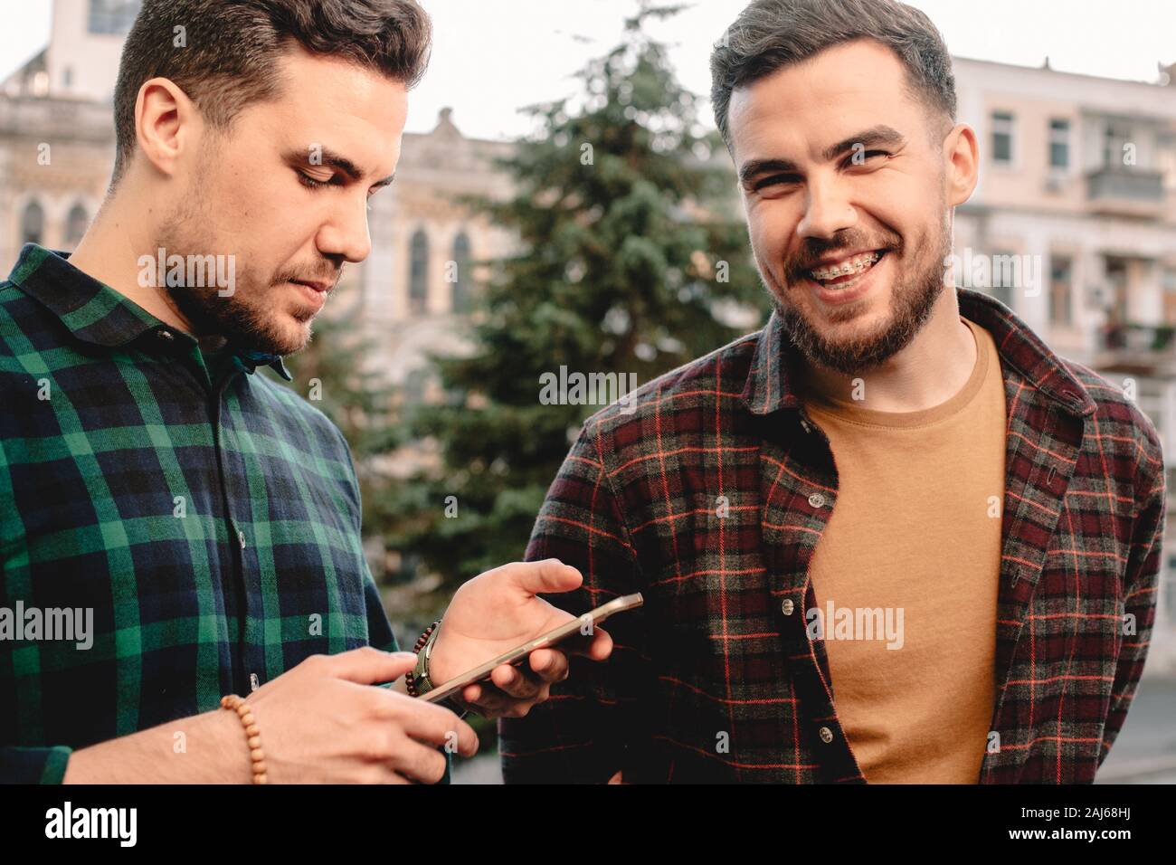 Man using smart phone while his brother standing beside him laughing Stock Photo
