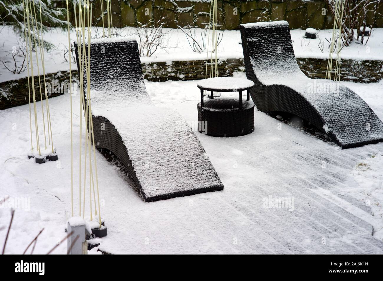 Two garden armchairs abandoned in a wibter garden under falling snow Stock Photo