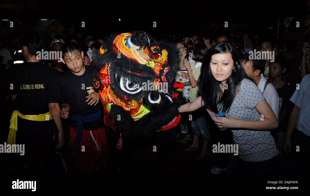 A woman put some money inside the head of a lion dance puppet in Chinese new year celebration festival. Stock Photo