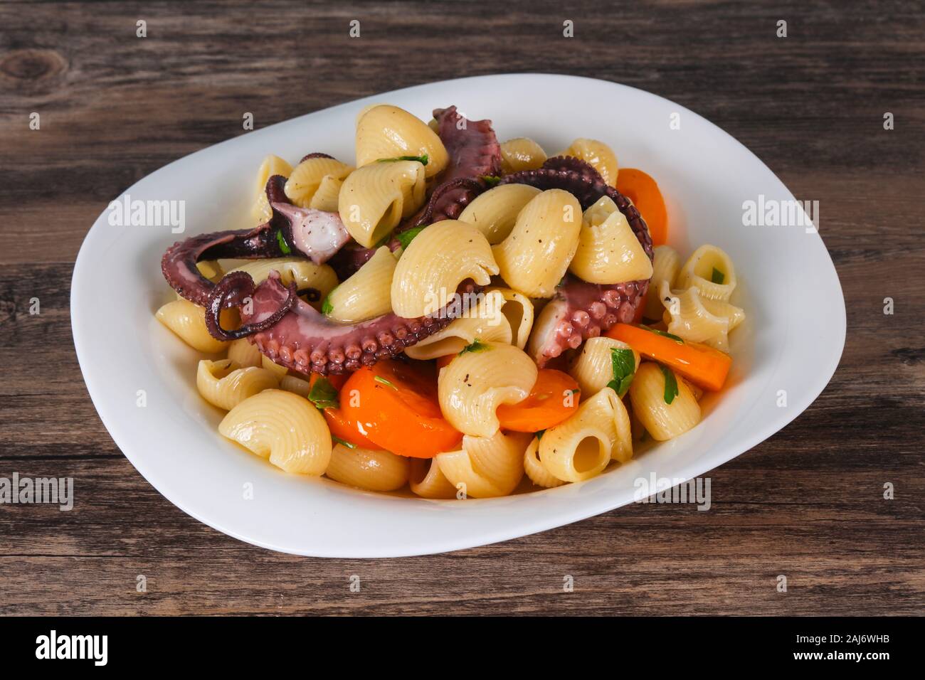 Pasta with octopus, parsley and yellow tomatoes Stock Photo - Alamy