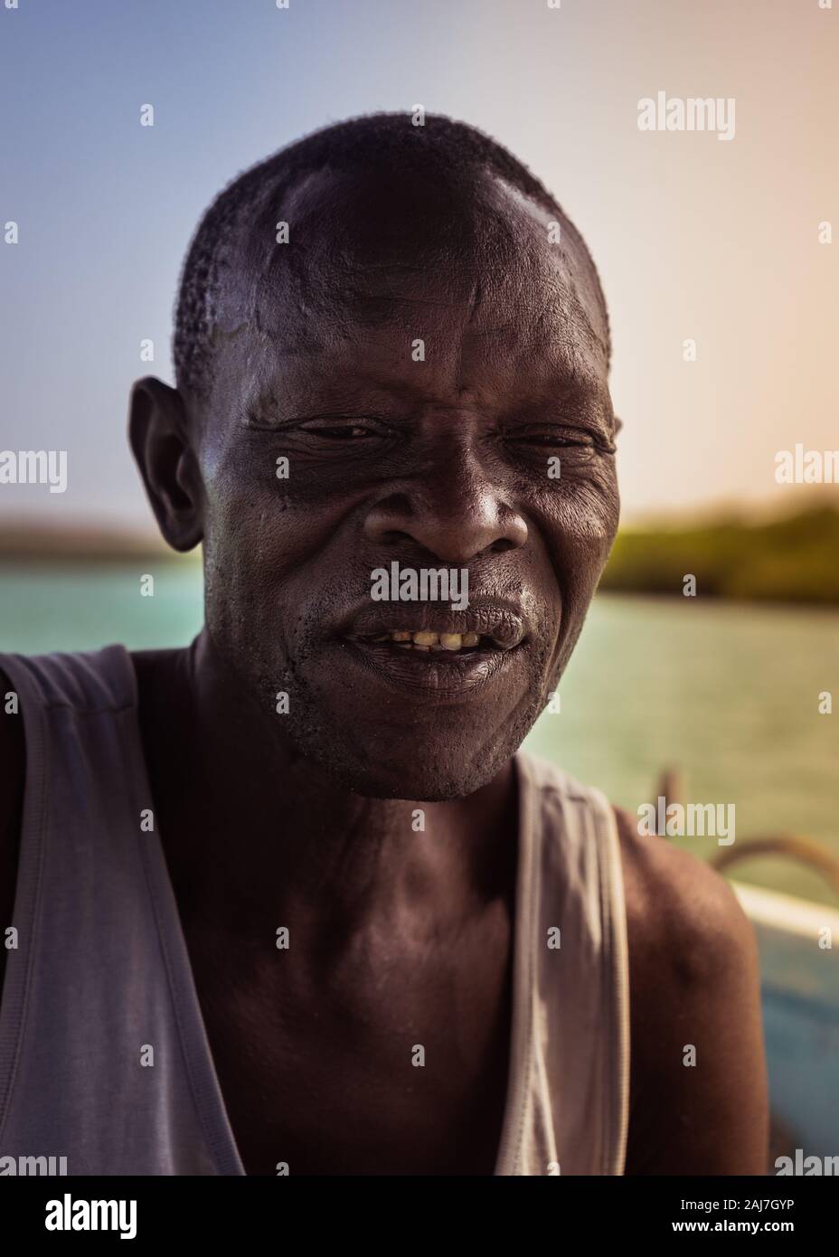 Characteristic and weathered face of the riverboat man on his boat on the river in Saly, Senegal, Africa - Photograph: Iris de Reus Stock Photo