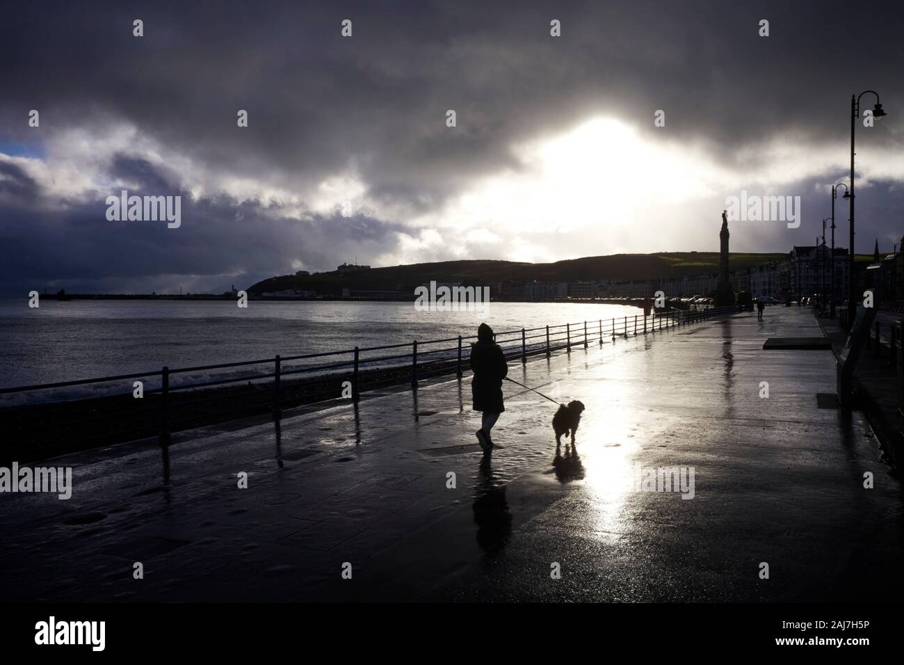 A woman walking a dog along the promenade at Douglas, Isle of Man Stock Photo