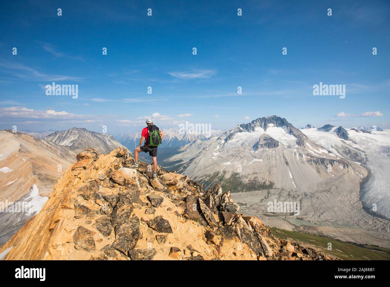 Rear view of hiker on mountain summit. Stock Photo