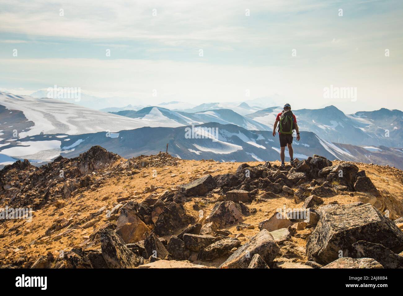 Hiker walking across mountain summit ridge. Stock Photo