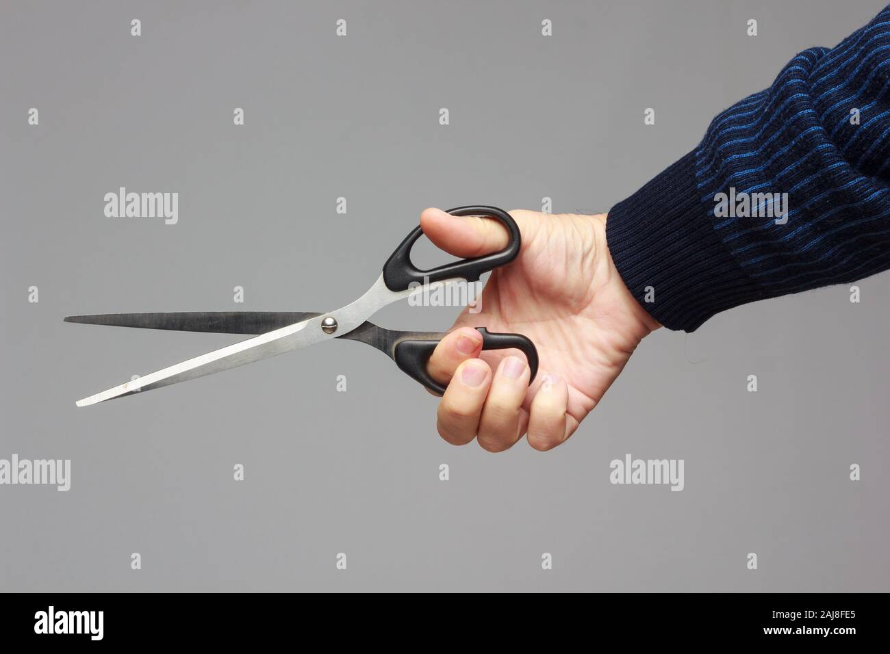 Large professional scissors in a person's hand, prepared to cut or trim