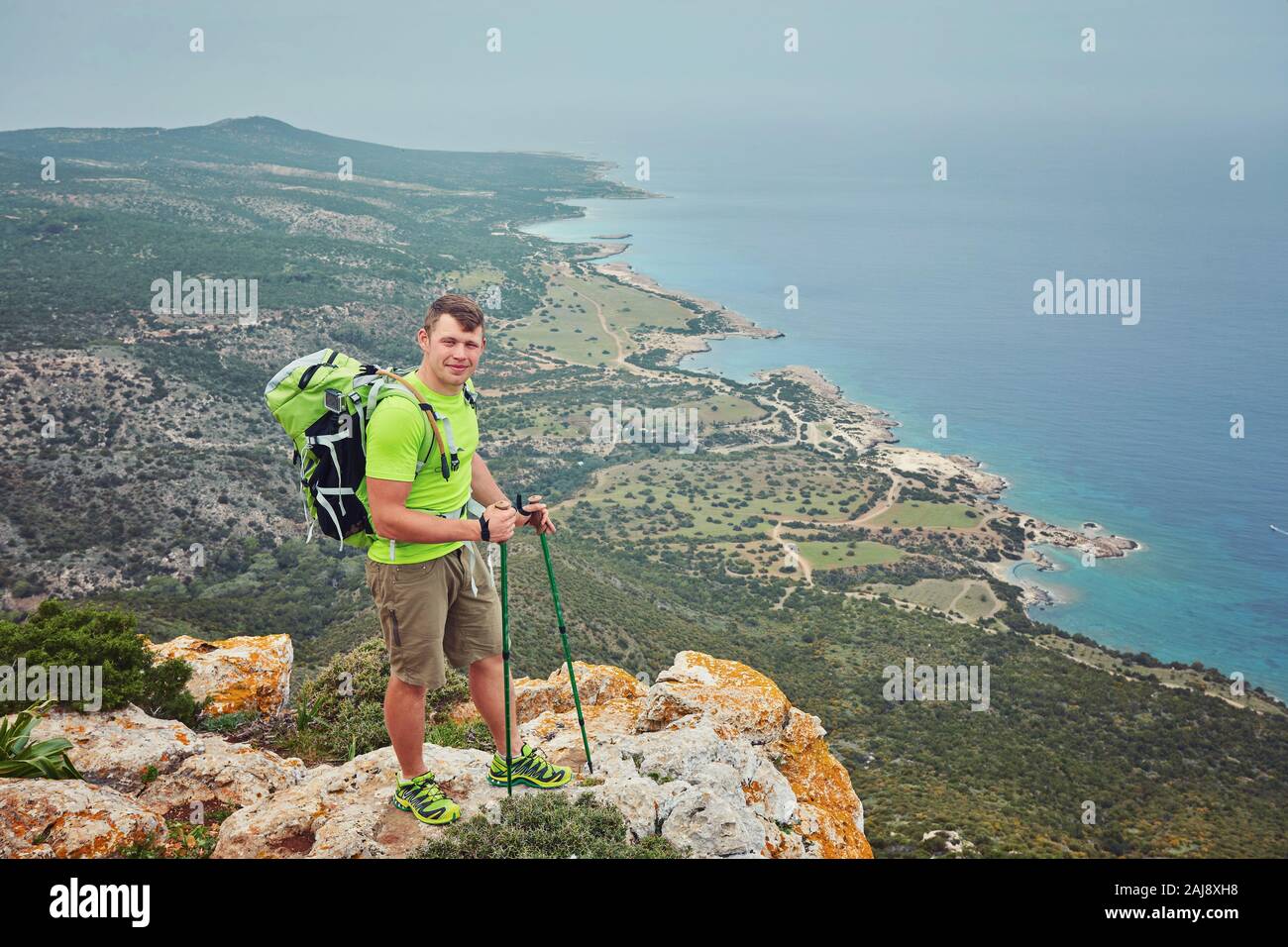 Hiker with backpack standing on top of a mountain with raised hands and ...