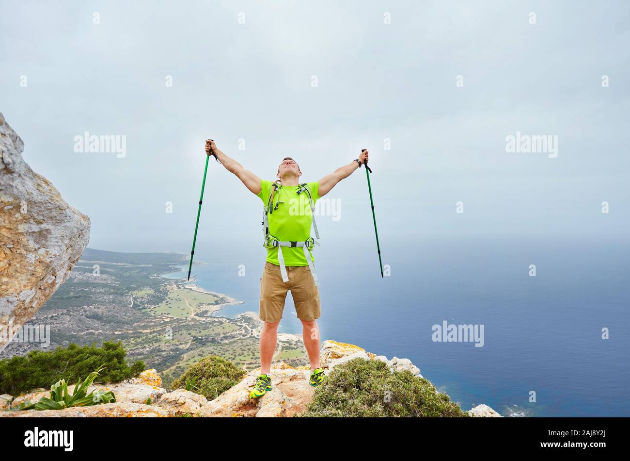 Hiker with backpack standing on top of a mountain with raised hands and ...
