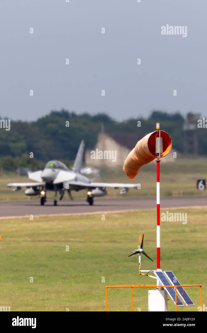 Windsock at RAF Coningsby with a Royal Air Force (RAF) Eurofighter EF-2000 Typhoon fighter aircraft lands in the background. Stock Photo