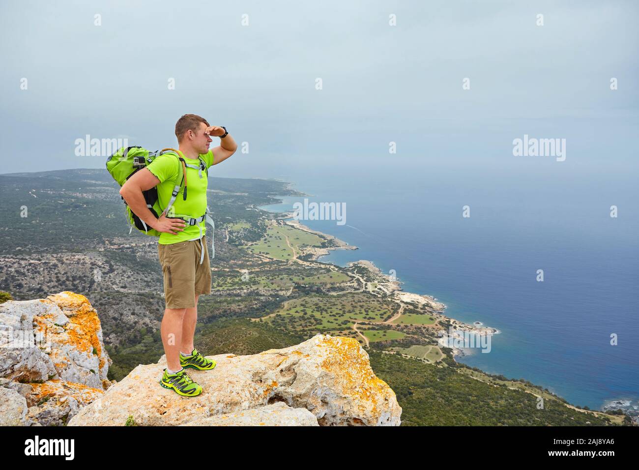 Hiker with backpack standing on top of a mountain with raised hands and ...