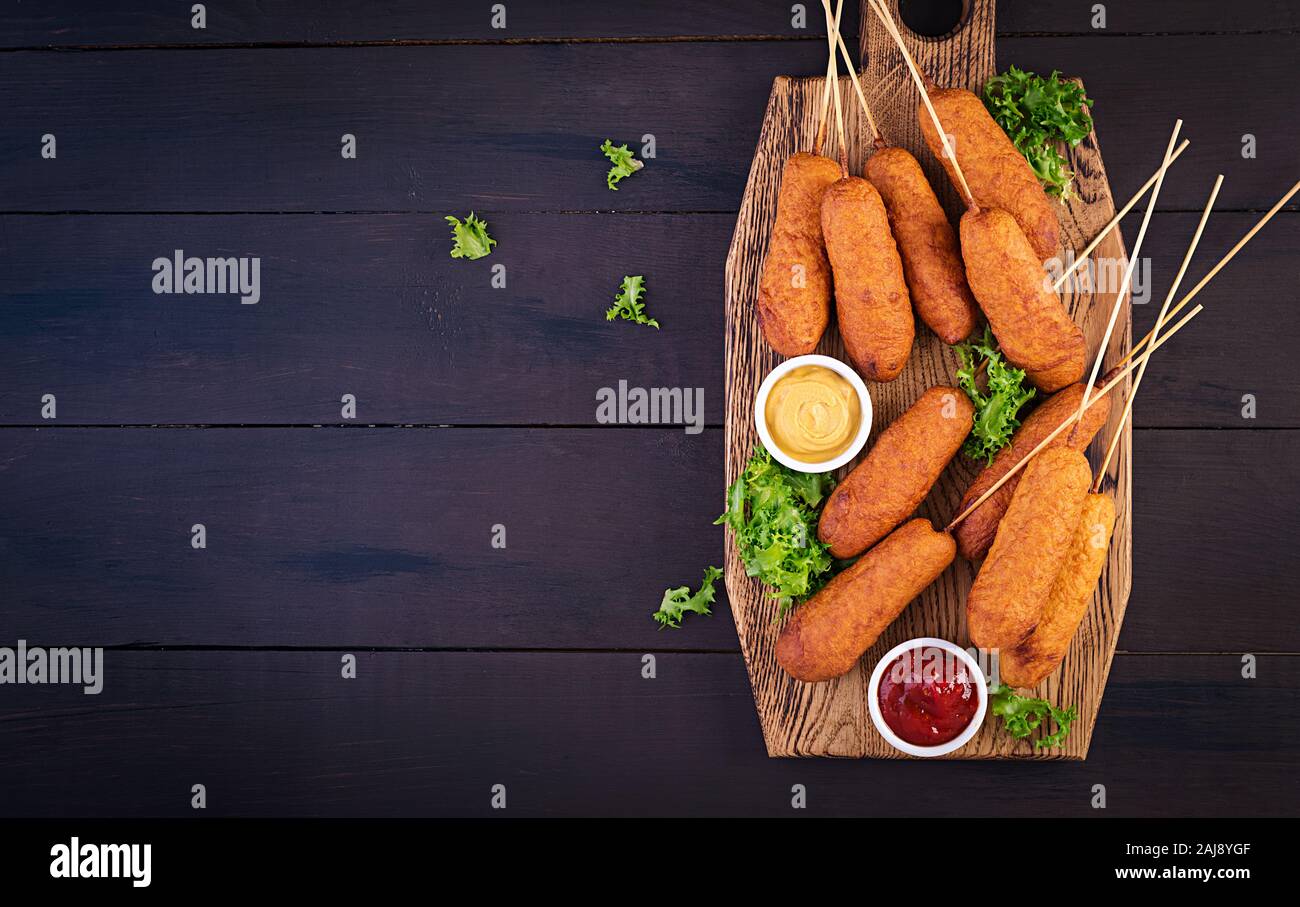 Traditional American corn dogs with mustard and ketchup on wooden board. Street food. Top view, copy space Stock Photo