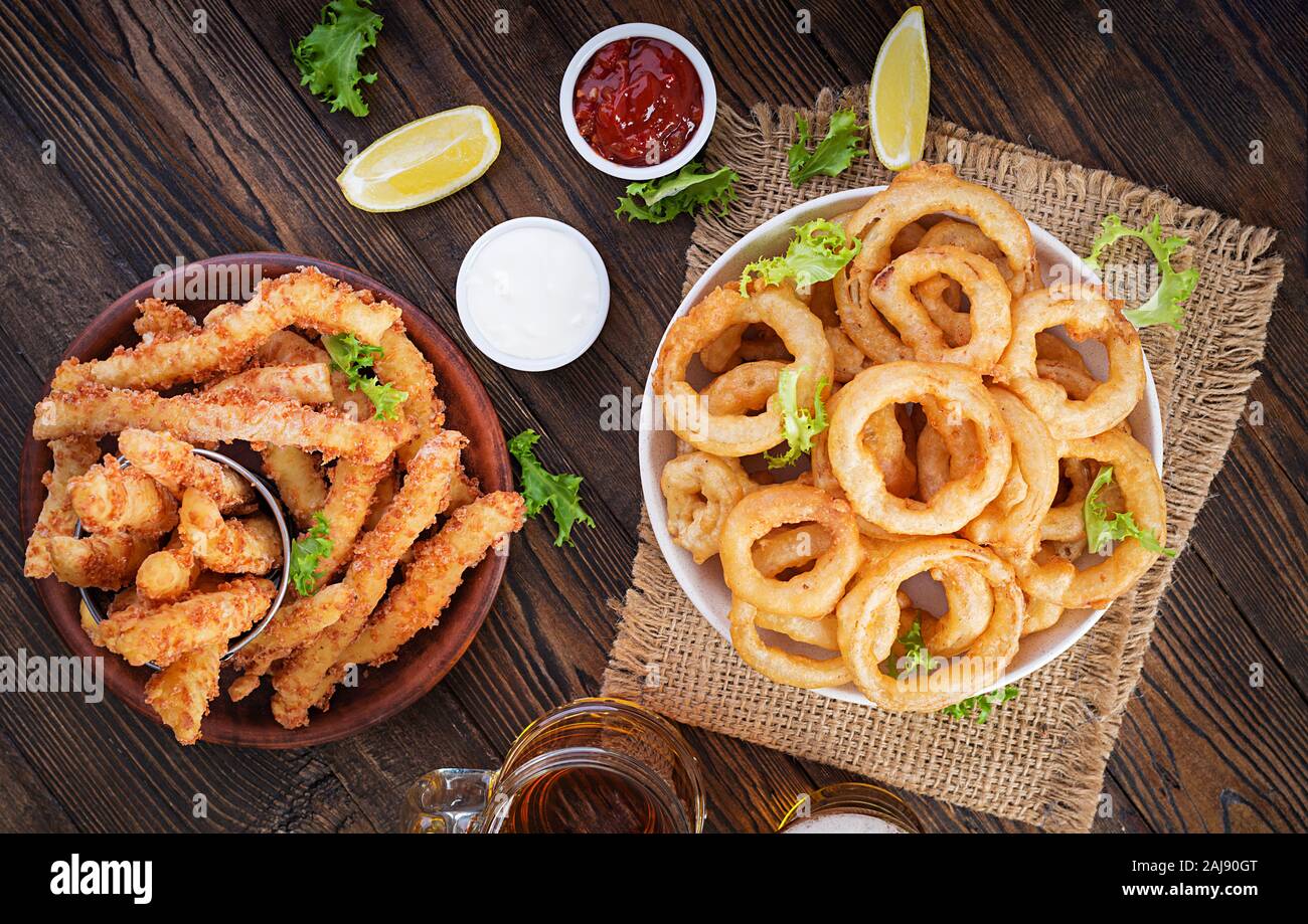 Onion rings in batter with sauce and cheese sticks. Beer snacks. Top view, overhead, copy space Stock Photo