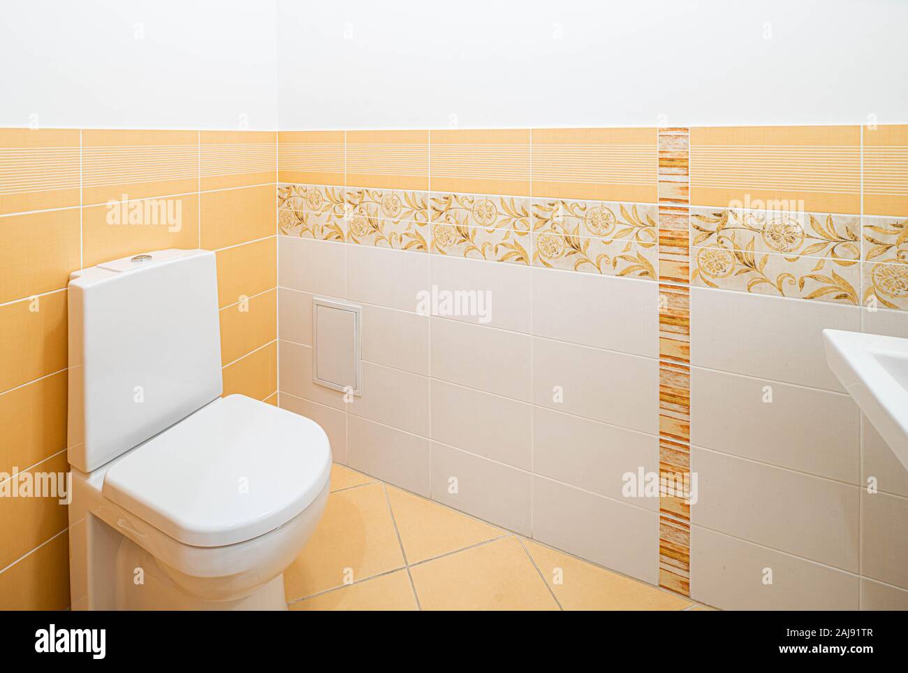 White toilet in bathroom. Light peach tile on the wall and floor. Stock Photo