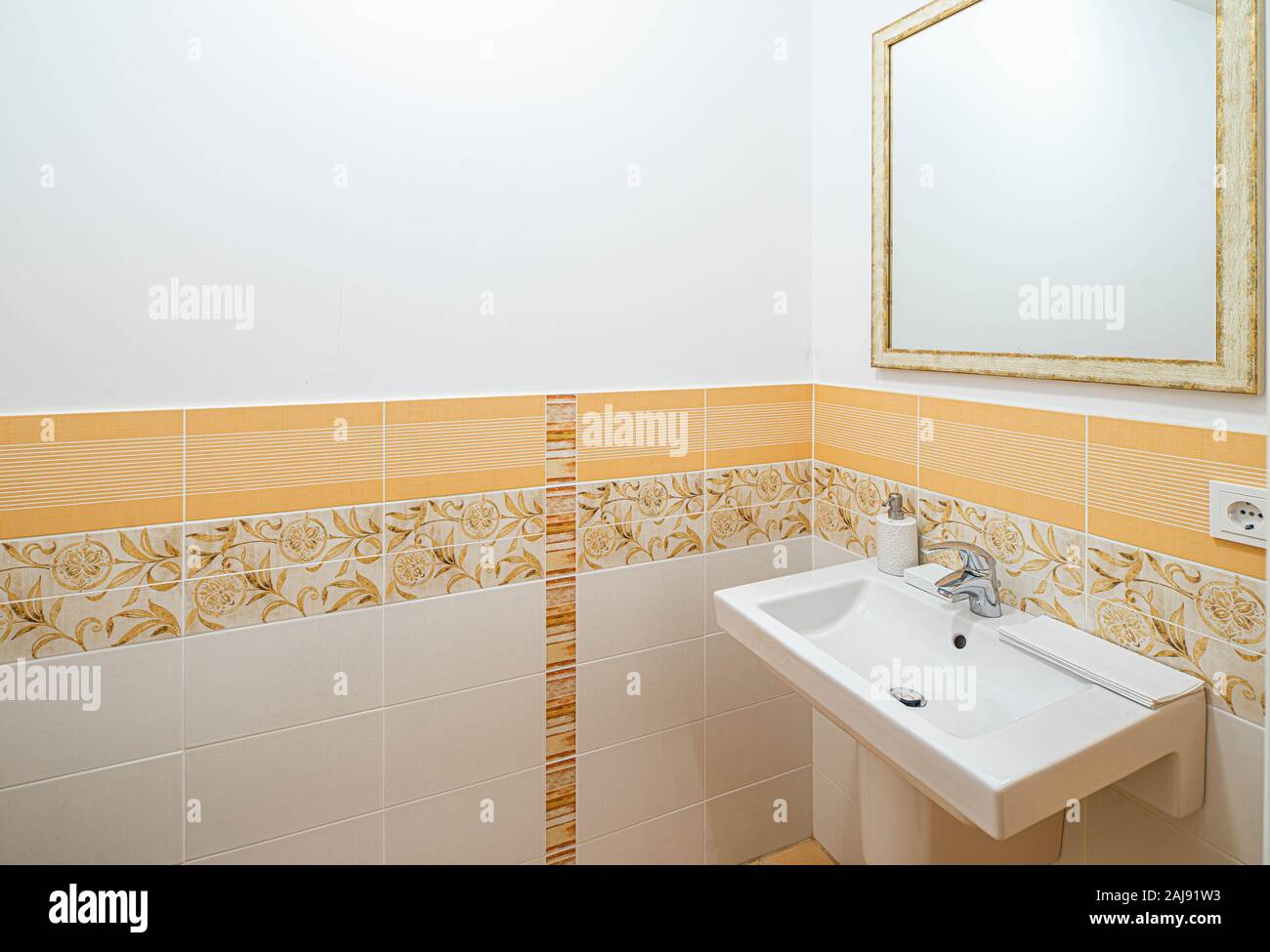 White sink and mirror in bathroom. Light peach tile on the wall. Stock Photo