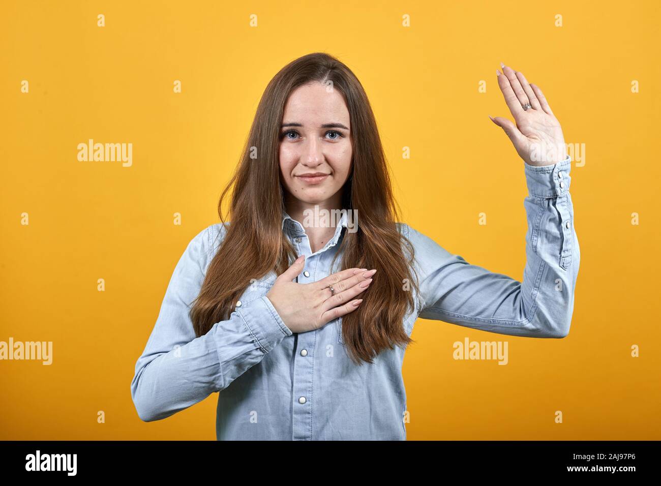 Attractive woman giving promise, keeping hand on chest and shoing palm at camera Stock Photo