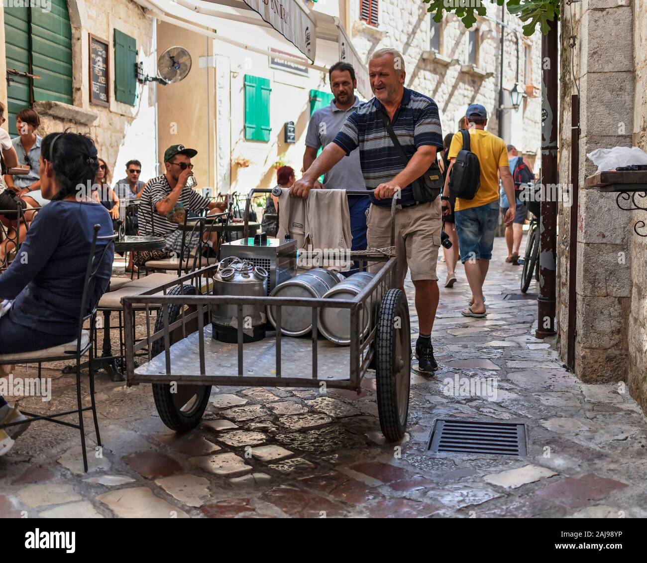 Montenegro, Sep 21, 2019: Street scene with a local man delivering beer kegs via wheel cart in Kotor Old Town Stock Photo