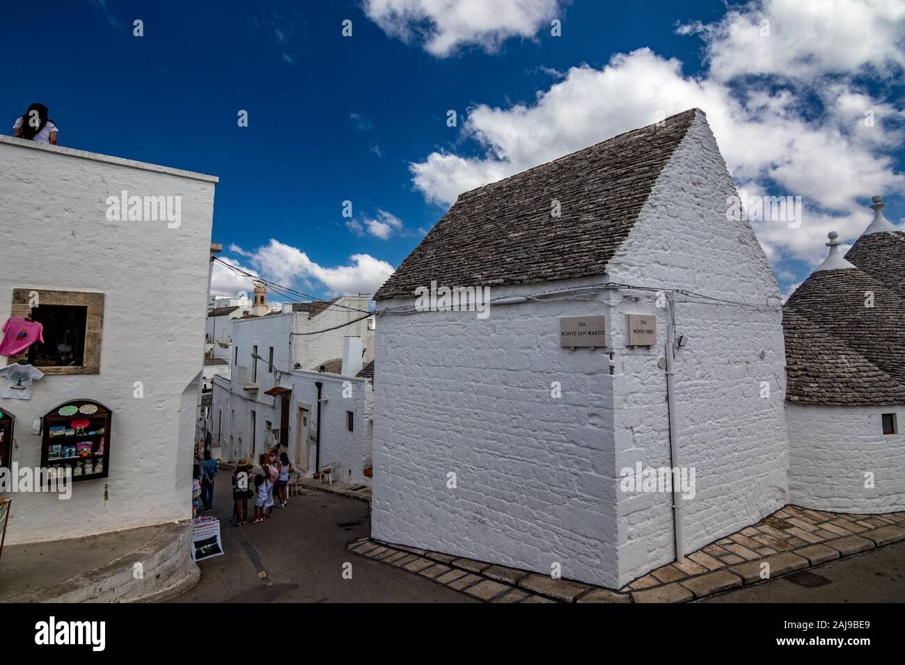 ALBEROBELLO, ITALY - AUGUST 28, 2018 - Beautiful old town with amazing whitewashed Trulli cone stone tiles roof houses in Apulia is visited each year by millions of tourists. Corner street house Stock Photo