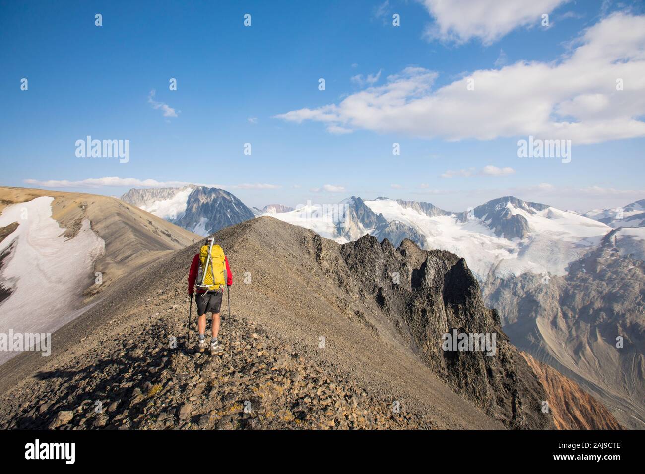 Rear view of backpacker hiking on rocky summit ridge. Stock Photo