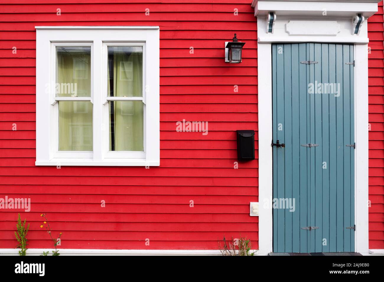 Facade of a red house in St John's, Newfoundland and Labrador, Canada. The house has a grey door. Stock Photo