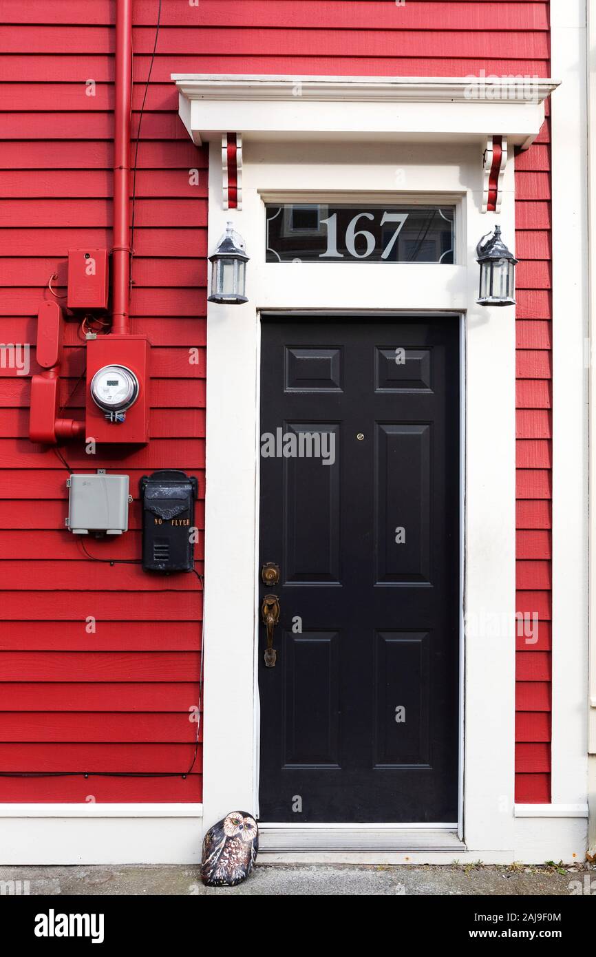 Facade of a red house in St John's, Newfoundland and Labrador, Canada. The house has a black door. Stock Photo