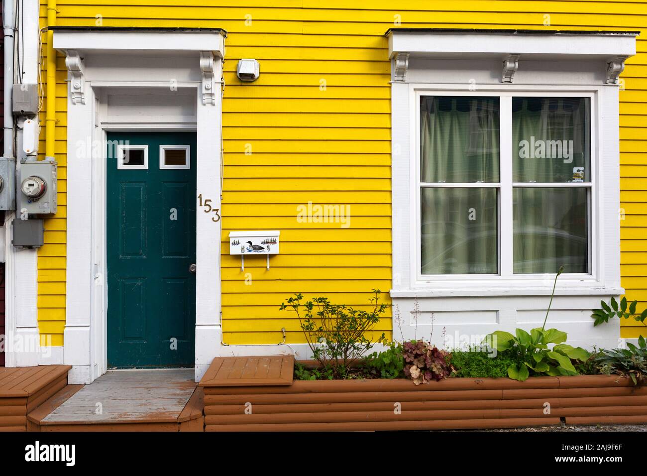 Facade of a yellow house in St John's, Newfoundland and Labrador, Canada. The house has a white window. Stock Photo